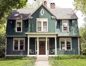 Charming antique victorian home with green shutters and cream colored siding.