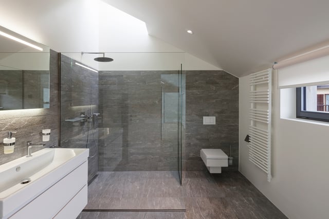 Large shower goes wall to wall, with towel warmer and glass panel.