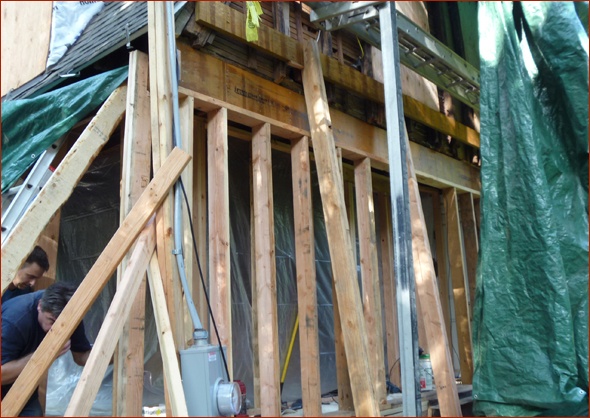 Workers protect the antique home, while building a new wall.