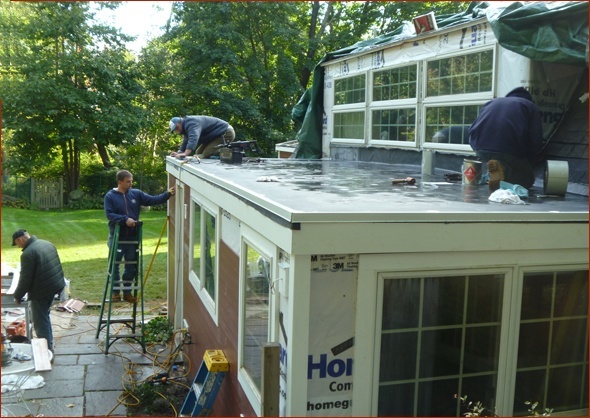 Workers complete the EPDM roof, siding and exterior trim.