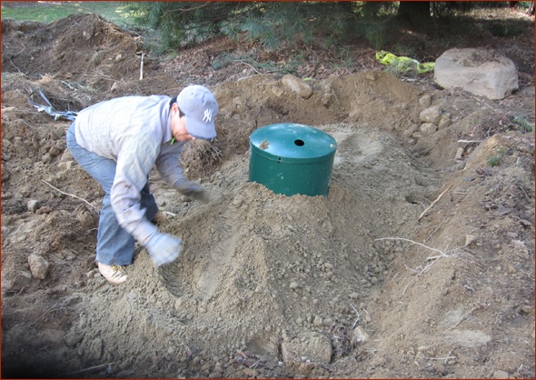 Final touches on filling in the dirt around the propane tank.