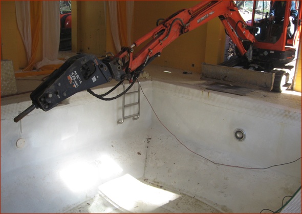Hydraulic hammer gets ready to break up sides of pool. 