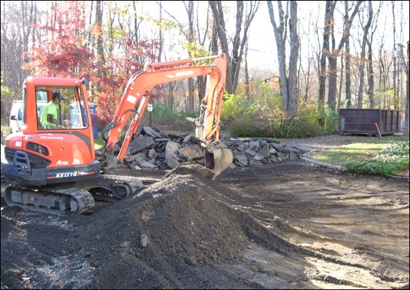 Excavator removes the asphalt driveway