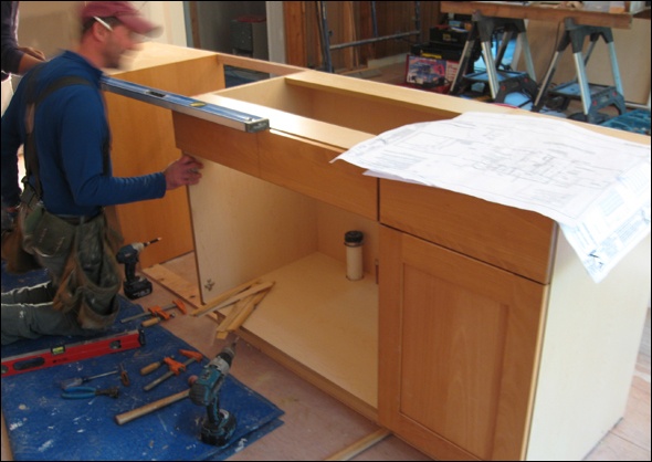 Carpenter refers to his plans for kitchen designs.