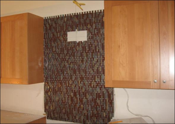 Glass tile backsplash at the range hood with transitional cabinetry