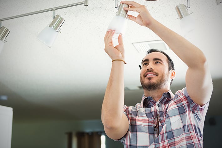 Contractor in a plaid shirt installing a light bulb - easy task for any homeowner once you know which light bulb to use.