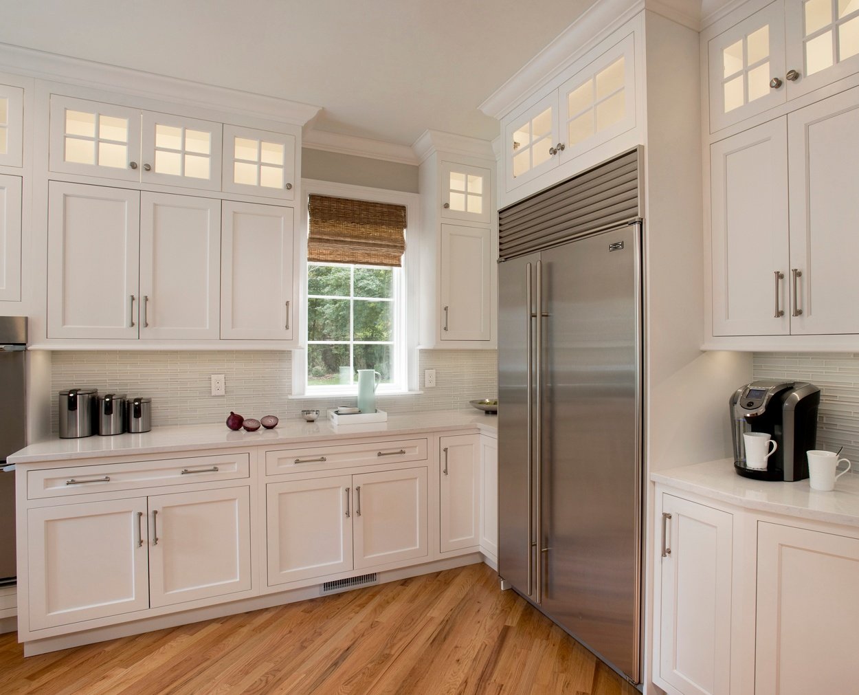 The corner of a classic white kitchen with Subzero refrigerator