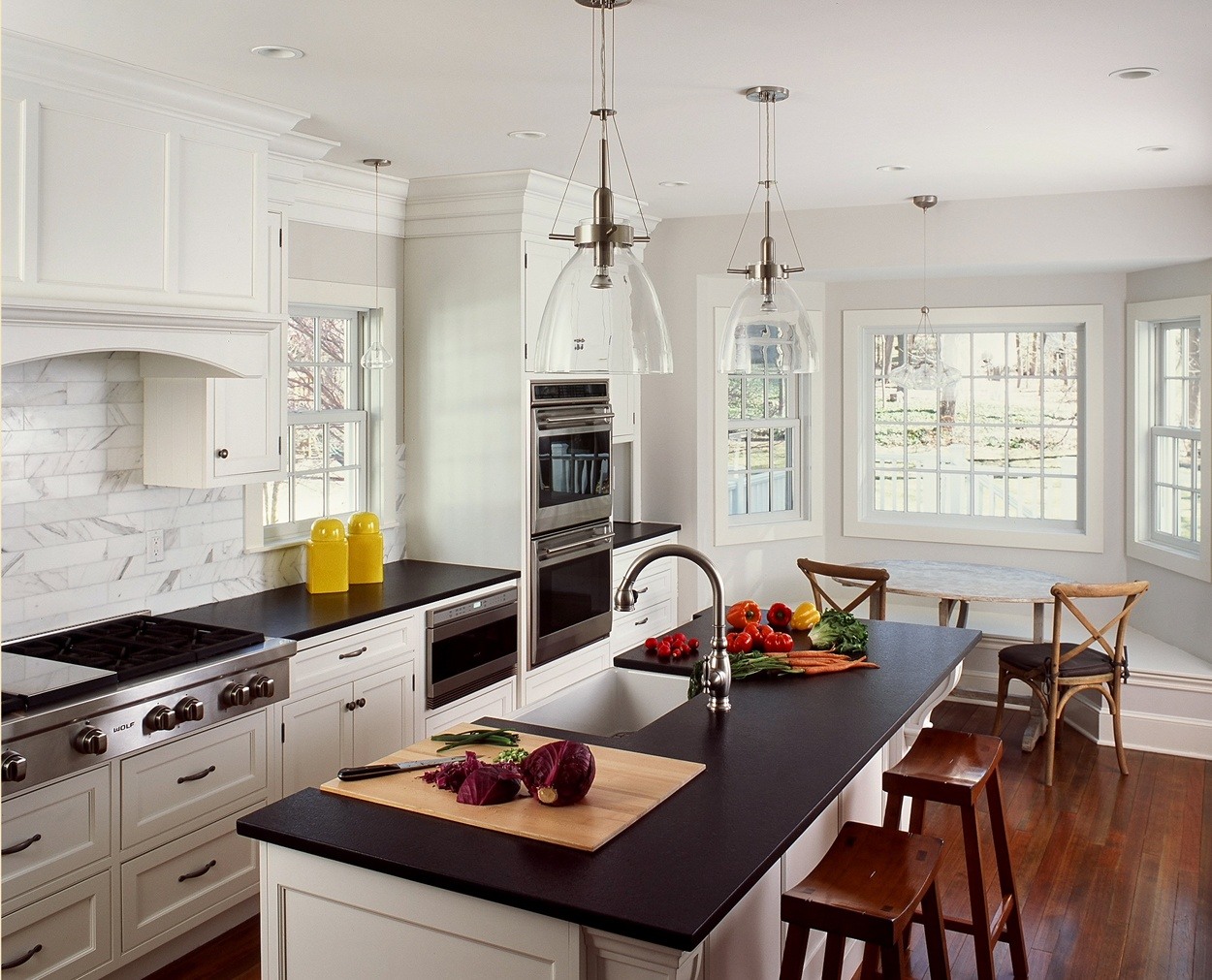 Center island with butcher block inlay, prep sink and adjacent banquette.