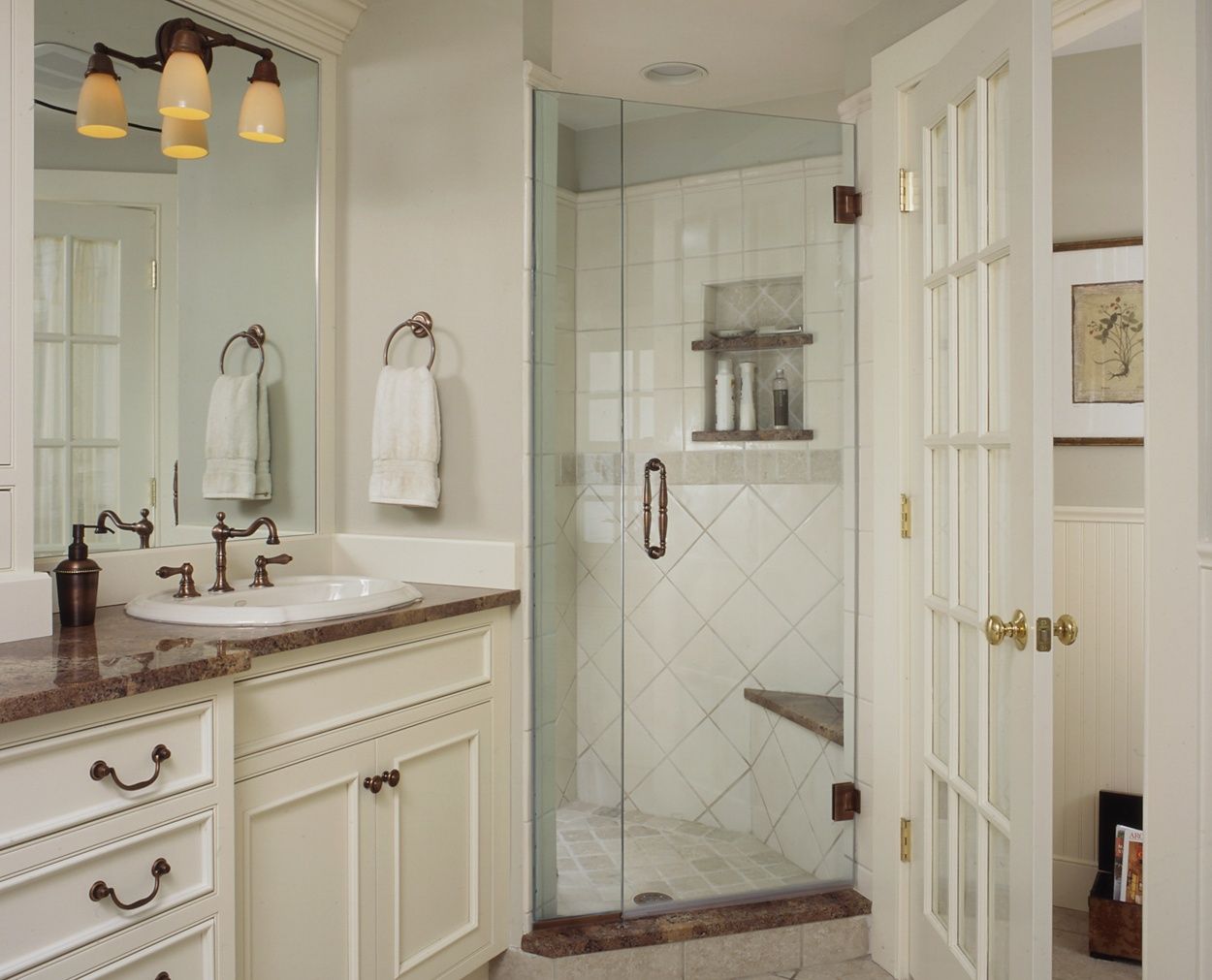 Corner frameless shower, with glass doored toilet room and traditional cabinetry.